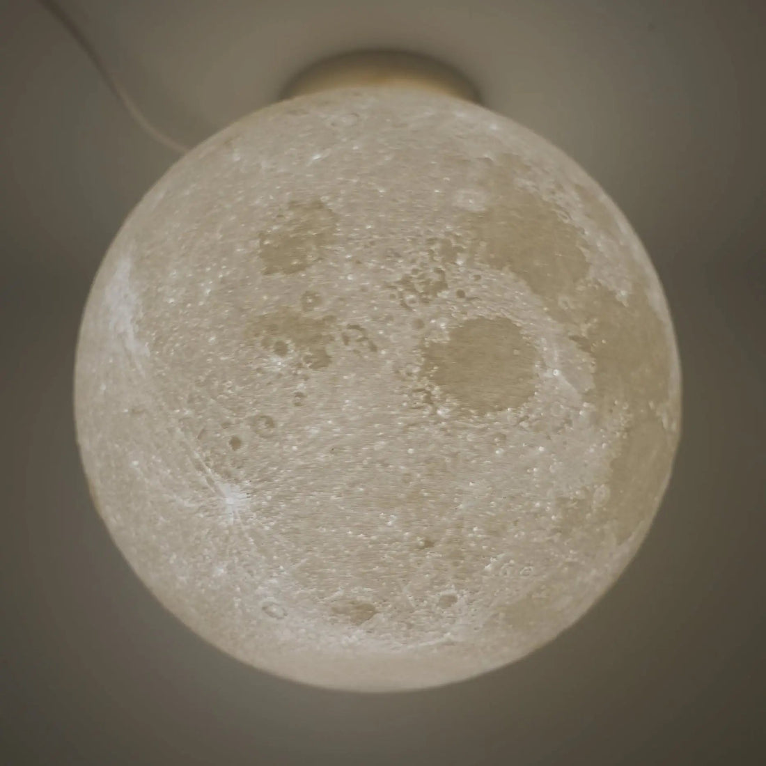 White spherical moon ceiling lamp with a cratered surface, suited to a nursery