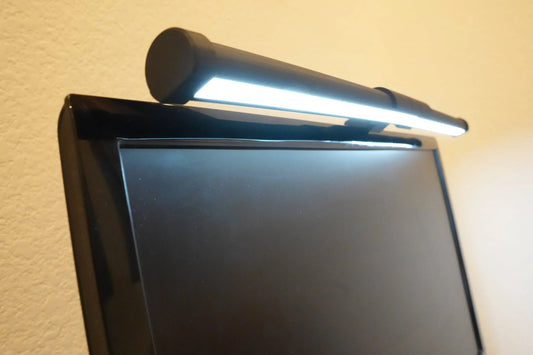 Sancticraft monitor reading light bar clamped to the top of a monitor, lighting the desk below