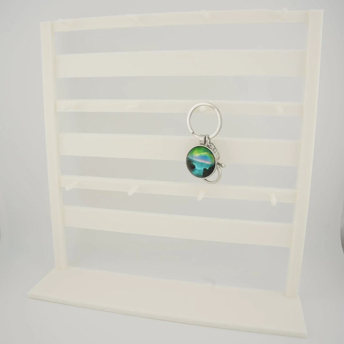 White tabletop keychain display rack with horizontal bars and front pegs for hanging charms