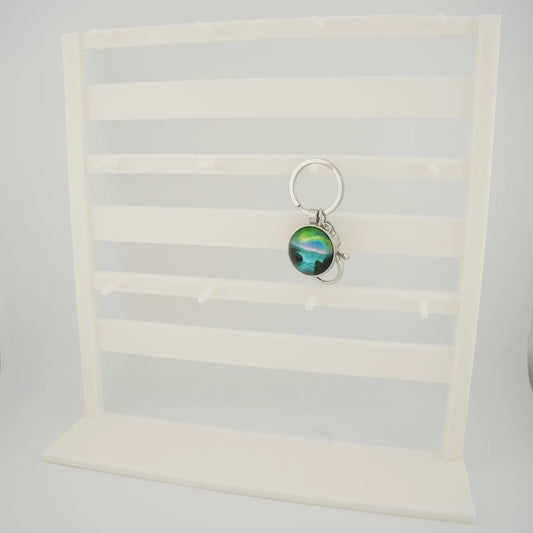 White tabletop keychain display rack with horizontal bars and front pegs for hanging charms