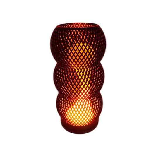 Sculptural lamp with a black lattice shell and warm orange glow inside